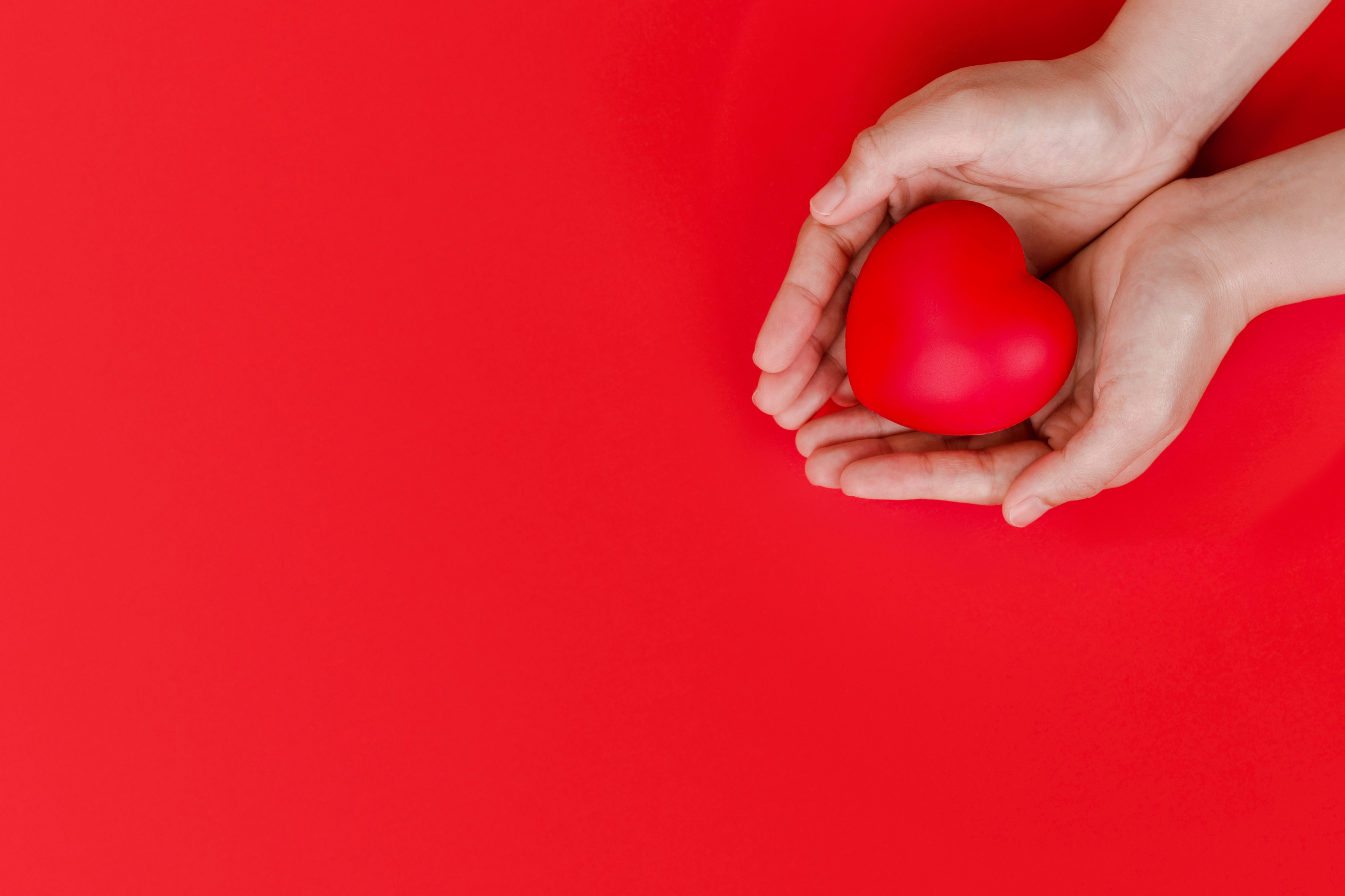 Person Holding a Heart on a Red Background